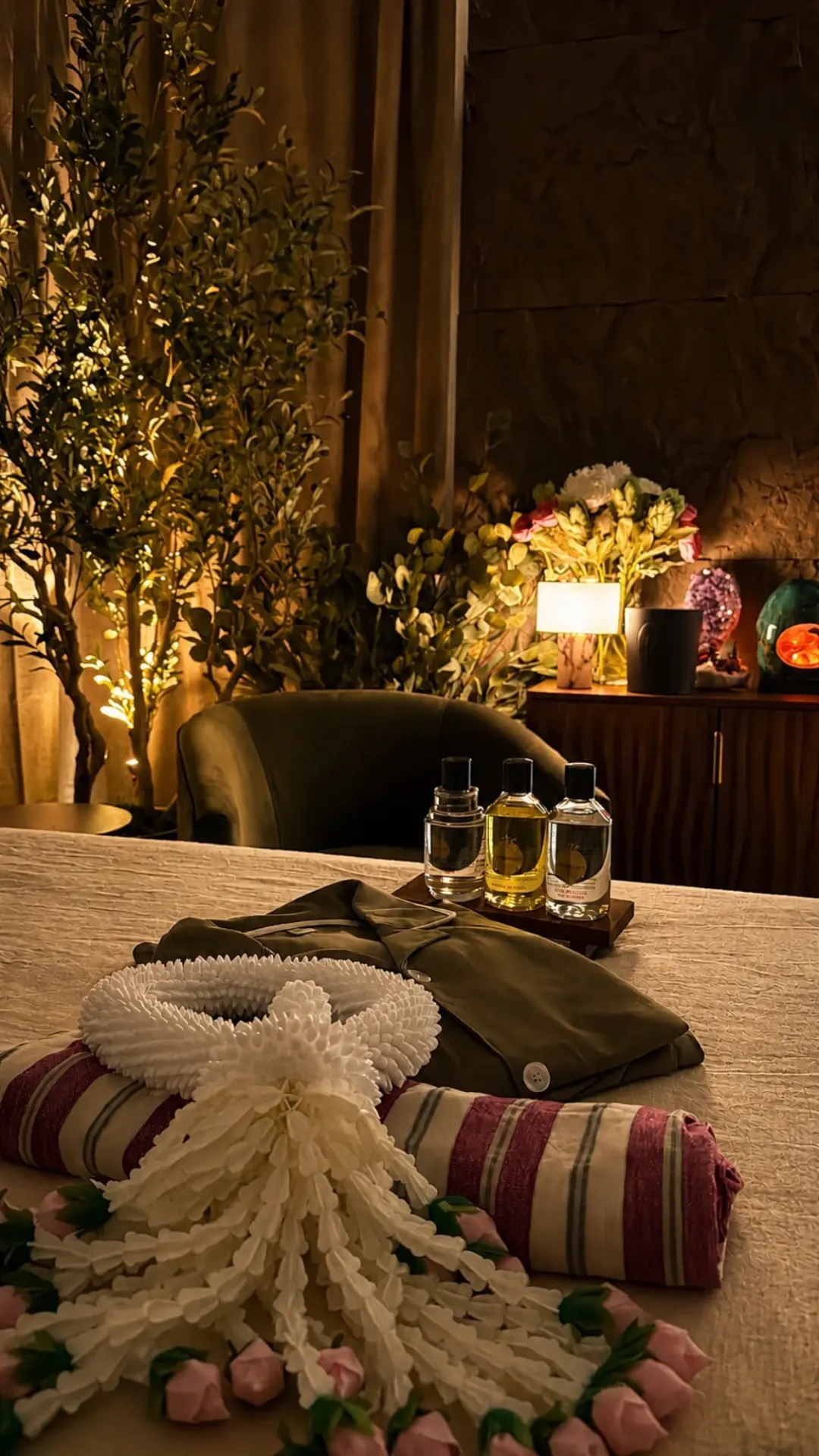 Spa treatment room with massage oils, folded robe, fresh flowers and warm candlelight